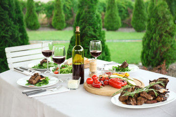 Delicious steak with wine on festive table outdoors