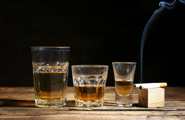 Glasses of alcohol and cigarettes on table