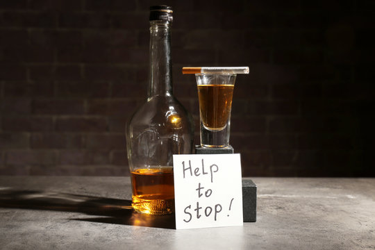 Note with words "Help to stop", alcohol and cigarette on table