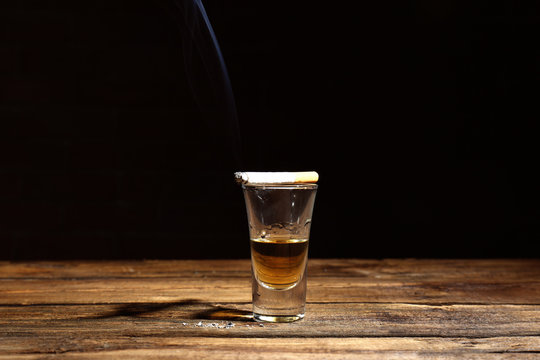 Glass of alcohol and cigarette on table