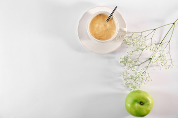 Cup of coffee, flowers and apple on table, top view. Tasty breakfast