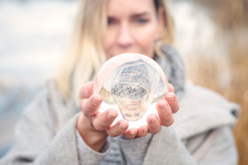 blond woman holding up a glass ball - Powered by Adobe
