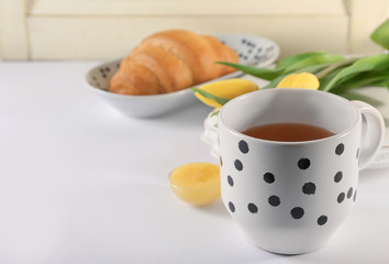 Cup of tea, croissant and honey on table. Tasty breakfast