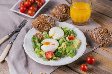 Poached egg with green salad, tomatoes, wholemeal bread and orange juice