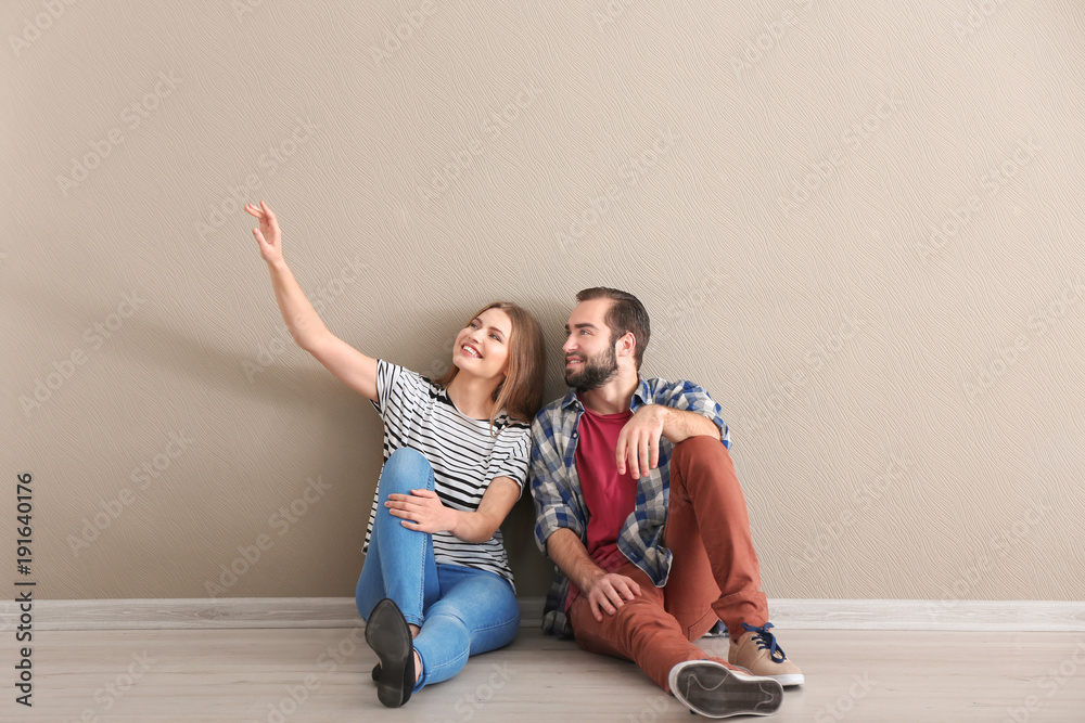 Poster young couple sitting on floor in empty room. ready for moving to new house