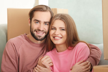 Young couple with moving boxes in room at new home