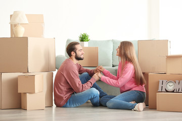 Fototapeta na wymiar Young couple with moving boxes on floor in room