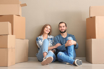 Fototapeta na wymiar Young couple with moving boxes on floor in room