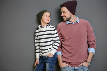 Stylish father and son on gray background