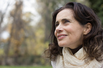 Portrait of mature woman with a vision look in her eyes at park during fall season. Intellectual...