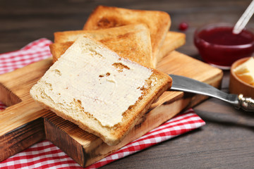 Wooden board with toasted bread on table