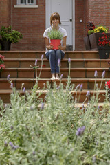 Mujer joven con plantas delante de su casa