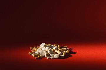 Medication white colorful round tablets arranged abstract on dark red color background. Aspirin,...