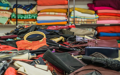 Verkauf Secondhand Grabbeltisch mit Taschen und gebrauchte Wolldecken auf einem Regal - Sale second-hand table with bags and used woollen blankets on a shelf