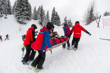 Photo sur Plexiglas Sports dhiver Kameraden der Bergwacht versorgen eine gestürzte und verletzte Skifahrerin