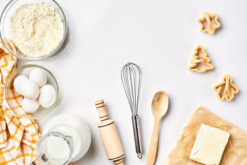 Objects and ingredients for baking, plastic molds for cookies on a white background. Flour, eggs, rolling pin, whisk, milk, butter, cream. Top view, space for text