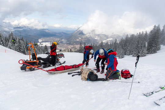 Kameraden der Bergwacht versorgen eine gest&uuml;rzte und verletzte Skifahrerin