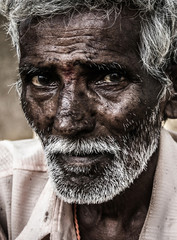 Portrait of elder Indian man with intense, deep look in his eyes, red bindi dot between them and white beard. Close up on old man with honesty, humble expression
