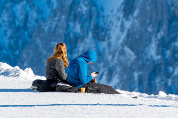 Junges Pärchen sitzt auf der Zugspitze und blickt ins Tal