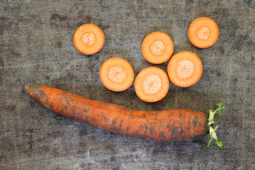 Winter carrot and some slices on a grungy metal background