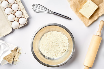 Preparation of the dough. A measurement of the amount of ingredients in the recipe. Ingredients for the dough: flour, eggs, rolling pin, whisk, butter. Top view, space for text