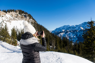 Fototapeta na wymiar Junge attraktive Frau macht Fotos mit Smartphone im Schnee