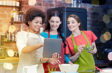 happy women with tablet pc cooking in kitchen