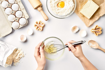 Fototapeta na wymiar Female chef whisking eggs in glass bowl on kitchen table