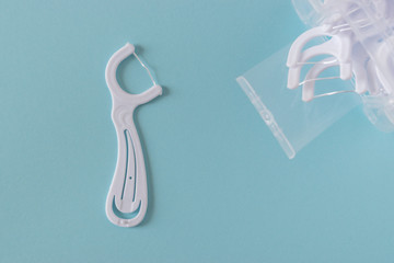 White dental flossers on bright blue background.