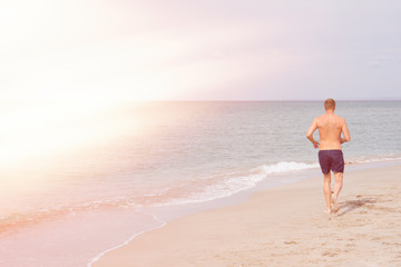 Fototapeta na wymiar Running and a healthy lifestyle. A man runs along the beach. 