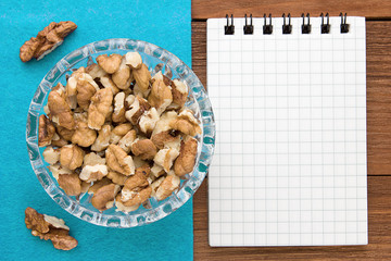Menu background. Cook book. Recipe notebook with walnuts on a blue background and a wooden board.