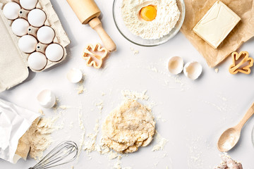 Raw dough ready for kneading on white table. Bakery ingredients, eggs, flour, butter. Shapes for making cookies.