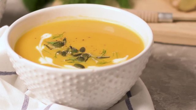 Delicious creamy homemade pumpkin soup with cream and pumpkin seed garnish.