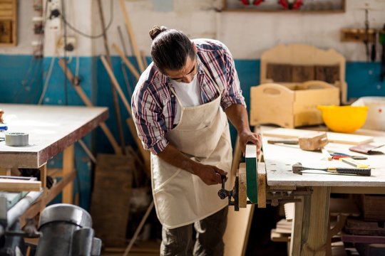 Carpenter working on wooden plank in workbench