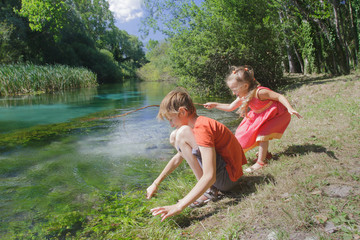 Girl and boy siblings playing near water of Italian Tirino river in Abruzzo