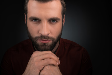 portrait of pensive man with hands in lock isolated on black