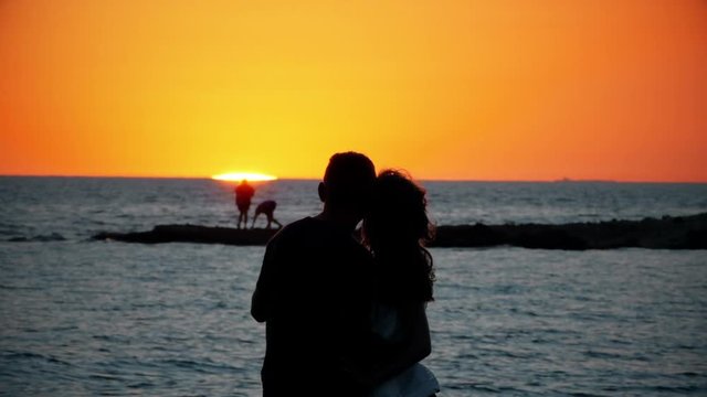 A breathtaking view of beach sunset. Young teenager couple standing on the background of amazing nature relaxing and enjoying vacation. Lovers silhouette,romantic atmosphere,charming ocean beauty