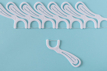 White dental flossers on bright blue background.