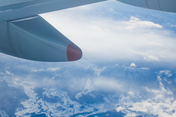 Naklejka na ściany i meble Plane window view of Mountains with snow and clouds - wintersports