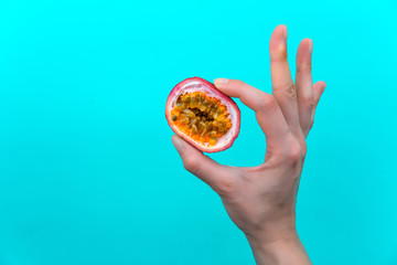 Female hand with Passion fruit on blue background