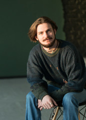 Portrait of hadsome young bearded stylish man sitting on the chair in studio