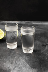 Cold vodka in shot glasses on a black background