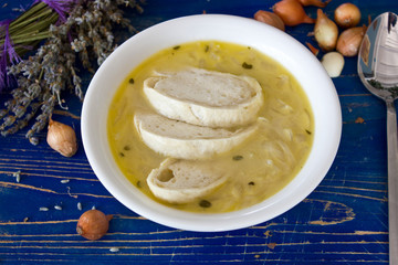 Traditional French onion soup with croutons. On a blue wooden board with lavender and bulbs