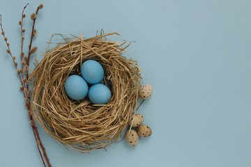 On a blue background lie three Easter eggs of blue color in a decorative nest