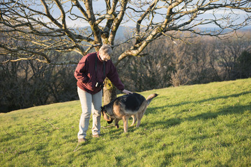 Mature woman playing with her pet Alsatian dog outdoors 