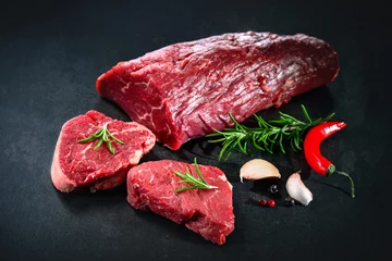 Gardinen Whole piece of tenderloin with steaks and spices ready to cook on dark background © Alexander Raths