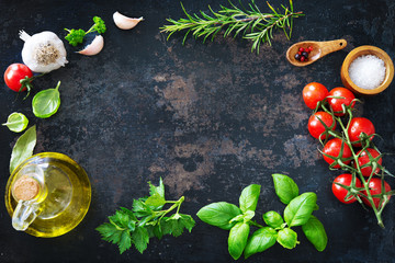 Olive oil, tomatoes, garlic, parsley, basil, spices on dark background