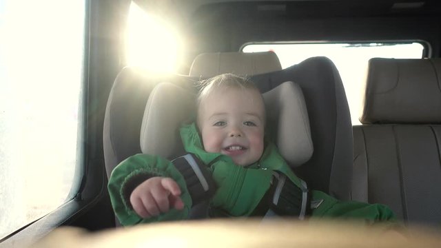 A beautiful child is riding in a car seat in a solar car