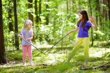 Two cute little sisters having fun during forest hike on beautiful summer day. Active family...