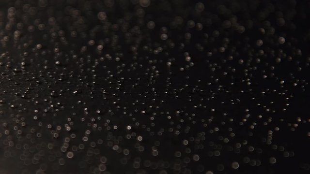 water drops on black surface. hitting the camera on small water droplets